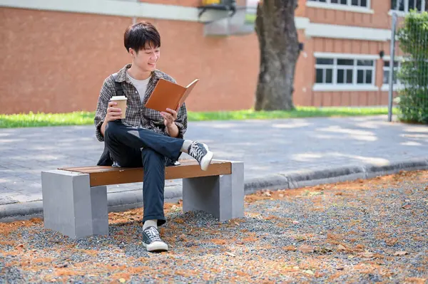 Счастливый Молодой Азиатский Студент Колледжа Наслаждается Кофе Читает Книгу Скамейке Стоковая Картинка