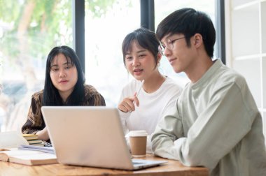 Bir grup Asyalı üniversite öğrencisi çalışma alanında otururken ya da sınıfta birlikte ders çalışırken iş ve fikirlerini paylaşıyorlar. Eğitim ve arkadaşlık kavramları