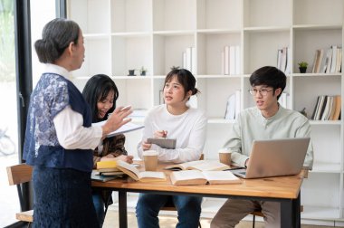 Genç bir Asyalı bayan üniversite öğrencisi sınıfta okurken öğretmeninin veya profesörünün sorusuna cevap veriyor. eğitim kavramı