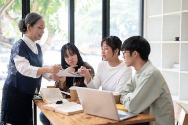 Bir grup şüpheci genç Asyalı üniversite öğrencisi deneyimli bir profesörle zor bir konuyu tartışıyor, sorular sorup, sınıfta ders çalışıyorlar. eğitim kavramı