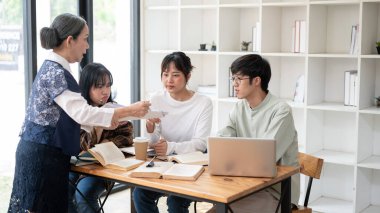 Bir grup şüpheci genç Asyalı üniversite öğrencisi deneyimli bir profesörle zor bir konuyu tartışıyor, sorular sorup, sınıfta ders çalışıyorlar. eğitim kavramı