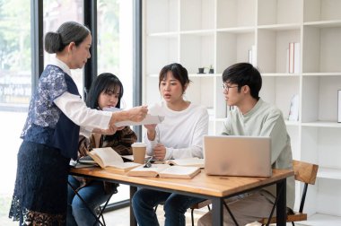 Bir grup şüpheci genç Asyalı üniversite öğrencisi deneyimli bir profesörle zor bir konuyu tartışıyor, sorular sorup, sınıfta ders çalışıyorlar. eğitim kavramı