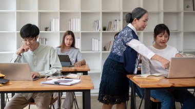 Deneyimli ve profesyonel olgun bir Asyalı bayan öğretmen veya profesör öğrencilerine zor bir matematik probleminde yardım ediyor. Eğitim ve kariyer kavramları