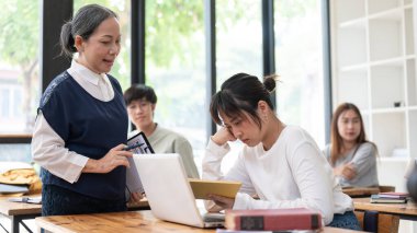 Genç öğrenci sınıfta ona yardım etmeye çalışırken dersi anlamaya çabalıyor. Eğitim kavramı.