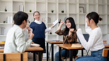 Neşeli, olgun bir Asyalı bayan öğretmen ya da profesör sınıftaki öğrencilerle iyi haberleri kutluyor. eğitim kavramı