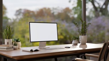 Beyaz ekran bir bilgisayar görüntüsü ve aksesuarlar, büyük cam pencereye karşı ahşap bir masanın üzerinde doğa manzaralı. Modern bir ofis, yakın plan görüntü. 3d görüntüleme, 3d illüstrasyon
