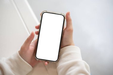 Beyaz kazaklı bir kadının beyaz ekranlı bir masayı kapalı bir şekilde beyaz ekranla kapatırken çekilmiş yakın plan görüntüsü. İçerde akıllı telefon kullanan bir kadın. İnsanlar ve kablosuz teknoloji kavramları