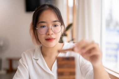 Kapalı bir masada tahta blok oyunu oynamaya odaklanan genç bir Asyalı kadın, tepesine tahta bir blok koyuyor. oyuncak, oyun, eğlence