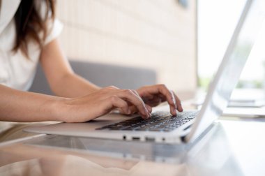 Laptop bilgisayarında çalışan, klavyede yazan, kahve dükkanında uzaktan çalışan bir kadının yakın plan görüntüsü. E-postalara cevap vermek, internette gezinmek, sohbet etmek.