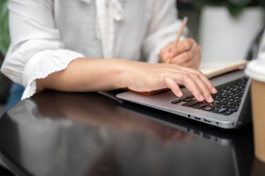 Not defterine ders notları yazıp internetten ders çalışan bir kız öğrencinin yakın plan fotoğrafı. insanlar ve teknoloji kavramları