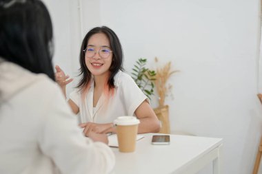 Neşeli ve arkadaş canlısı bir Asyalı kız üniversite öğrencisi bir proje üzerinde çalışmak için arkadaşıyla bir kafede buluşuyor, konuşuyor, proje hakkında konuşuyor ve fikirleri paylaşıyor..