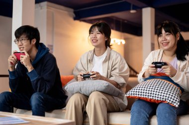 Bir grup genç, neşeli Asyalı arkadaş evde oyun oynayıp hafta sonları eğleniyorlar. ev hayatı, rahatlık, arkadaşlık.