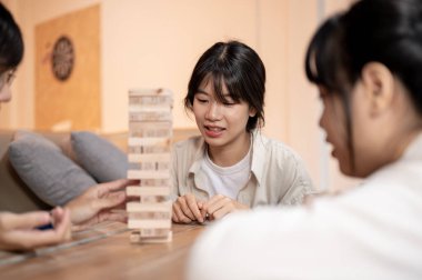 Genç, mutlu bir Asyalı kadın arkadaşlarıyla evlerinde tahta bloklar oynuyor. Arkadaşının tahta bir bloğu kaldırışını ve ahşap bir kule inşa edişini izliyor. Birlikte eğleniyor..