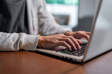 Laptop bilgisayarında çalışan, dizüstü bilgisayarında yazan, kapalı bir masada çalışan Asyalı bir adamın yakın plan görüntüsü..