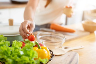 Mutfakta yemek yapan, salata yapan, elinde domates tutan bir kadın resmi. Ev yemekleri, sağlıklı yaşam tarzı, sağlıklı beslenme, kilo verme tarifleri, ev hayatı, boş zaman.