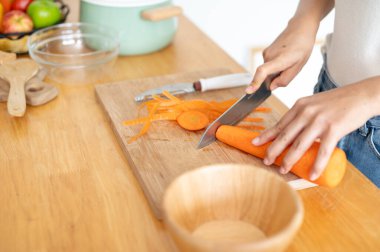 Kesme tahtasında havuç kesen, mutfakta yemek pişiren bir kadının yakın plan görüntüsü. Ev yemekleri, sağlıklı yaşam tarzı, sağlıklı beslenme, kilo verme tarifleri, ev hayatı, boş zaman.