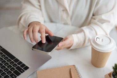 Kahve dükkanındaki bir masada akıllı telefonunu kullanan bir iş kadınının yakın plan görüntüsü. Kahve dükkanından uzaktan çalışıyor. İnsanlar ve kablosuz teknoloji kavramları