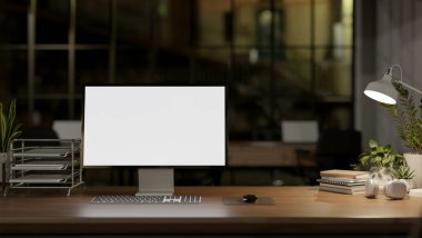 Geceleri çağdaş bir ofiste beyaz ekran modeli, ofis malzemeleri ve karanlık bir ofisteki lambadan loş bir ışık olan bir bilgisayar bulunur. 3d görüntüleme, 3d illüstrasyon