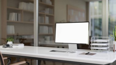 Modern ofis odasındaki bir bilgisayar masasında beyaz ekran maketi ve ofis malzemeleri olan bir bilgisayar bulunur. İş yeri konsepti. 3d görüntüleme, 3d illüstrasyon