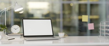 Modern bir ofiste beyaz ekran maketi ve aksesuarları olan bir dizüstü bilgisayar bulunur. iş yeri konsepti, 3D render, 3D illüstrasyon