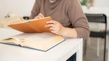 Kitap okuyan, bir kitaptan bilgi arayan, bir kafede ya da kütüphanede oturan bir kız öğrencinin kırpılmış görüntüsü. insanlar ve eğitim kavramları