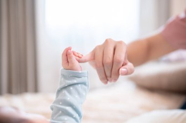 Annesinin parmağını tutan yeni doğmuş bir bebeğin fotokopi çekilen yakın plan fotoğrafı. Aile bağları, sevgi ve şefkat, ebeveynlik, birliktelik