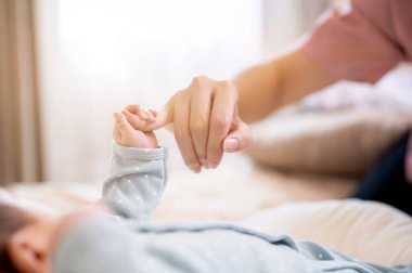 Annesinin parmağını tutan yeni doğmuş bir bebeğin fotokopi çekilen yakın plan fotoğrafı. Aile bağları, sevgi ve şefkat, ebeveynlik, birliktelik