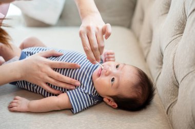 Yeni doğmuş bebeğinin ağzını ve dişlerini küçük bir fırçayla temizleyen şefkatli bir annenin yakın plan görüntüsü. annelik, çocuk bakımı, çocuk bakımı konsepti