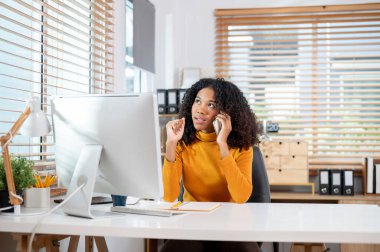 Çekici, ciddi bir siyahi iş kadını ofisinde iş müşterisiyle telefonda konuşuyor. Telefon üzerinden iş yapmak, telefona cevap vermek.
