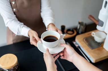 Kahve dükkanında çalışan bir müşteriye kahve fincanı uzatan bir bayan baristanın yakın plan görüntüsü. hizmet, küçük işletme, yarı zamanlı iş