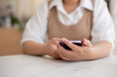 Kafedeki bir masada oturan ve akıllı telefonunu kullanan bir kadının kırpılmış görüntüsü. sohbet, online alışveriş, telefondan kaydırma, mobil uygulama kullanarak