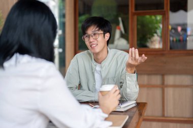 Genç bir Asyalı meslektaşı ile gayri resmi bir görüşme yapıyor, ortak proje için fikirler tartışıyorlar..
