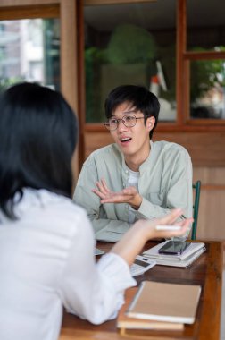 Genç bir Asyalı meslektaşı ile gayri resmi bir görüşme yapıyor, ortak proje için fikirler tartışıyorlar..