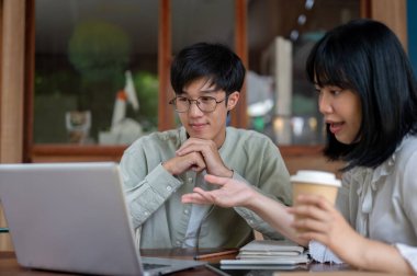 Olumlu, zeki bir Asyalı genç adam, bayan meslektaşının proje hakkındaki fikirlerini dinlerken, bir kafede birlikte çalışırlar..