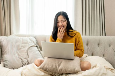 Güzel, neşeli Asyalı bir kadın film izlerken ya da arkadaşlarıyla oturma odasındaki bir kanepede dizüstü bilgisayarında sohbet ederken gülüyor. İnsanlar, teknoloji ve yaşam tarzı