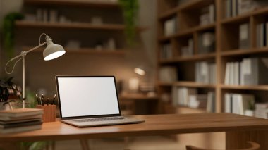 Geniş bir kitaplığı olan rahat bir ofis odasındaki ahşap bir masanın üzerinde beyaz ekran maketi ve kırtasiyesi olan bir dizüstü bilgisayarın yakın çekim görüntüsü. 3d görüntüleme, 3d illüstrasyon