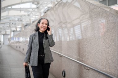 Başarılı, olgun bir Asyalı iş kadını müşterisiyle telefonda konuşurken hava yürüyüşü ya da hava tren istasyonunda dolup taşan bir şehirde işe giderken konuşuyor..