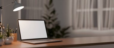 Beyaz ekranlı bir dizüstü bilgisayarın yakın plan görüntüsü ve alacakaranlıkta bir odada ahşap bir masadaki lambayla aydınlatılmış. 3d görüntüleme, 3d illüstrasyon