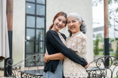 Mutlu, kibar, olgun bir Asyalı büyükanne güzel torununa güzel bir evde sarılıyor ve evde birlikte vakit geçiriyor. Sevgiyle kucaklaş, büyükanne ve büyükbaba ev ziyareti, aile bağı