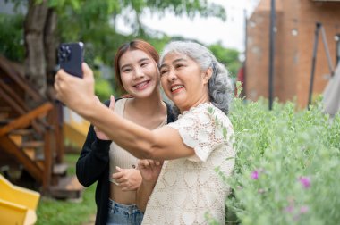 Sevimli bir Asyalı büyükanne torunuyla birlikte bahçede takılıp evde mutlu vakit geçirirken selfie çekiyor ya da video kaydediyor. Aile bağları, insanlar ve kablosuz teknoloji