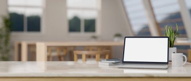 Bir masa, asgari çalışma alanına sahip beyaz ekran maketi, bir kupa, kitaplar ve bir dekor bitkisine sahip bir dizüstü bilgisayara sahiptir. 3d görüntüleme, 3d illüstrasyon