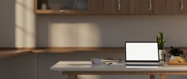 Çağdaş, minimalist bir mutfakta mutfak masasında beyaz ekran maketi ve dekoru olan bir dizüstü bilgisayar. ev işyeri konsepti. 3d görüntüleme, 3d illüstrasyon