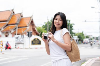 Tayland 'ın eski kenti Chiang Mai' de, sokakta elinde bir kamerayla gezen, sıradan giyinmiş, güzel bir Asyalı kadın var..