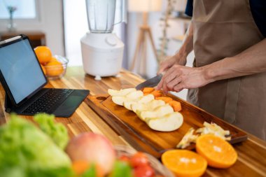Mutfak masasında yemek hazırlarken dijital tabletindeki tarifi kontrol eden bir adamın yakın plan görüntüsü. ev hayatı, yaşam tarzları, sağlıklı yiyecekler.