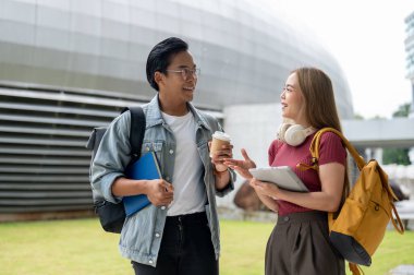 İki neşeli Asyalı genç üniversite öğrencisi, bir erkek ve bir kadın, günlük giysiler içinde, kampüs binası boyunca birlikte yürürken sohbet ediyorlar. Eğitim ve arkadaşlık kavramları