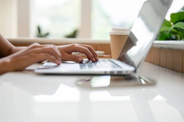 Kahve dükkanında dizüstü bilgisayarında çalışan, kahve dükkanında uzaktan çalışan, dizüstü bilgisayarında yazan, e-postalara cevap veren ya da internet sitesine göz atan bir kadının yakın plan fotoğrafı..