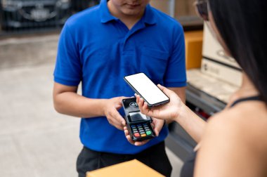 Teslimatçıdan bir paket almadan önce akıllı telefonunu kart okuyucusuyla dinleyen bir müşterinin yakın plan görüntüsü. kablosuz ödeme ve nakliye hizmeti kavramları