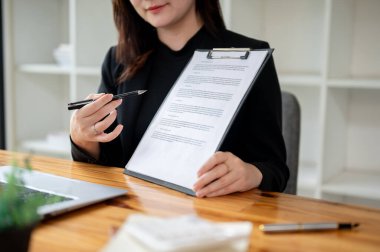 Profesyonel, güzel bir emlakçının, bir müşteriye kontratı gösterip açıklarken çekilmiş görüntüsü..