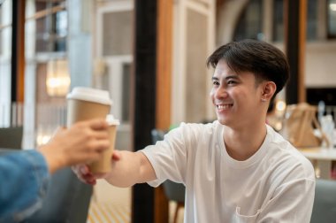 Bir kafede buluşurken arkadaşıyla kahve içen mutlu ve yakışıklı bir Asyalı. Arkadaşlık, arkadaşlık, takım çalışması, birliktelik, rahatlık.