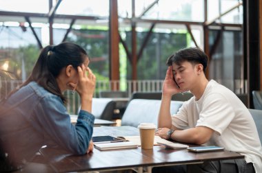 Ciddi, stresli Asyalı bir adam, meslektaşının iş ile ilgili sorunları tartışmasını dinliyor. Çözüm bulmak için birlikte çalışıyorlar. Hayal kırıklığını ve baş ağrısını ifade ediyorlar..